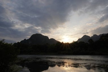bulutlu gökyüzü ile günbatımı arka planda dağların görünümü 