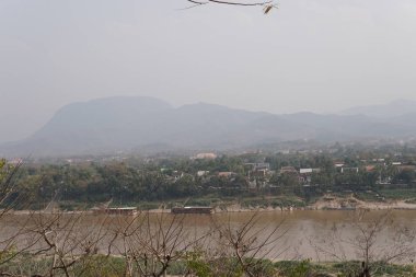 bulutlu bir günde yeşil ağaçlar ve evler ile tepelerin havadan görünümü