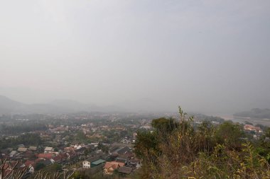 bulutlu bir günde yeşil ağaçlar ve evler ile tepelerin havadan görünümü