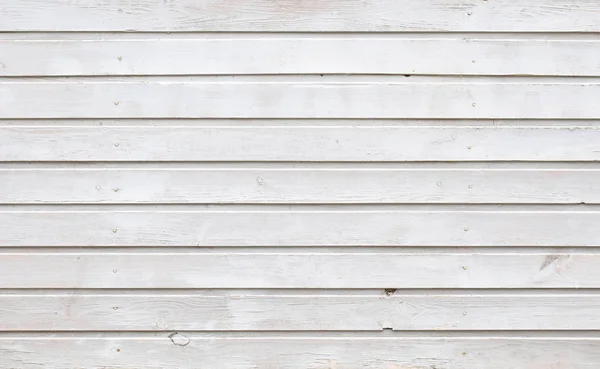 The unique texture of painted white oil paint wooden planks of the old building with ranks rows of hammered nails