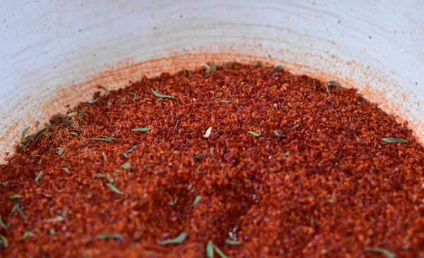 Red grains of dried fragrant spices in a white clay bowl close-up