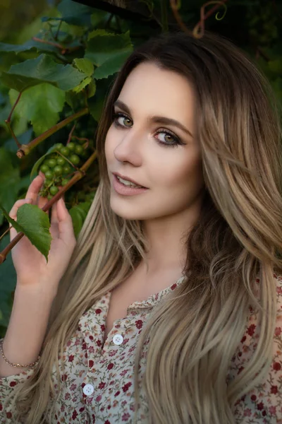 Italian style photo shoot - portrait of a young blonde girl with bunches of grapes close-up