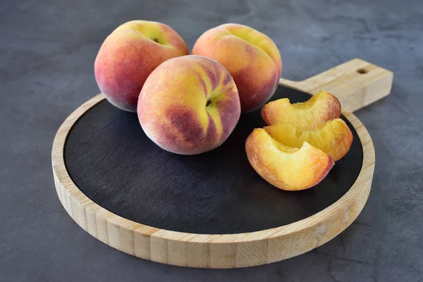 Tender, velvety peaches with juicy pulp on a wooden cutting board close-up