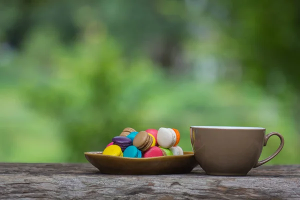 Cup of coffee and Colorful Macaroons in dish on wooden table — Stock Photo, Image