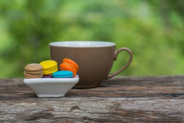 Ahşap masa üzerinde çanak kahve ve Renkli Macaroons Fincan
