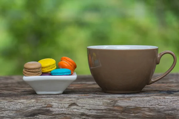 Cup of coffee and Colorful Macaroons in dish on wooden table — Stock Photo, Image