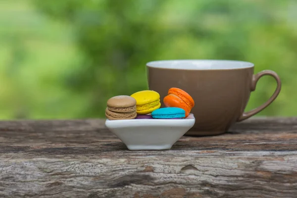 Cup of coffee and Colorful Macaroons in dish on wooden table — Stock Photo, Image