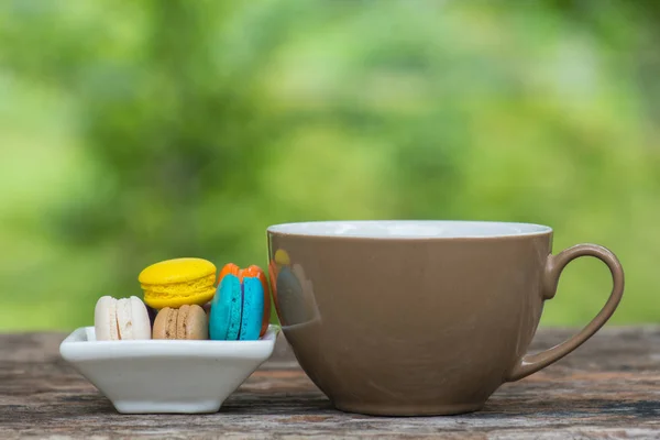 Cup of coffee and Colorful Macaroons in dish on wooden table — Stock Photo, Image