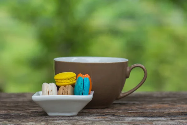 Cup of coffee and Colorful Macaroons in dish on wooden table — Stock Photo, Image