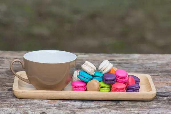 Cup of coffee and Colorful Macaroons in dish on wooden table — Stock Photo, Image