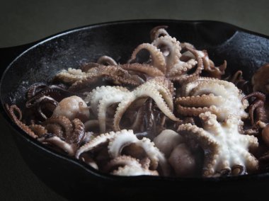 Bir dökme demir tava kavurma sürecinde mini ahtapot.