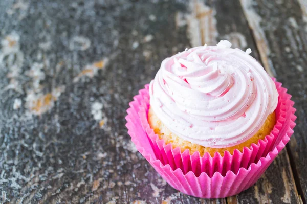 Cupcake de coco com creme de coalhada rosa no fundo de madeira — Fotografia de Stock