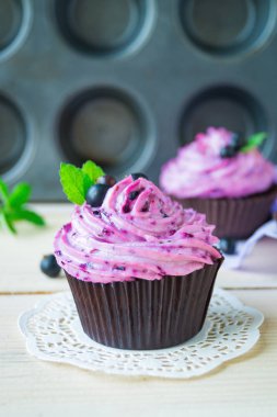 Ahşap arka plan üzerinde lor krema ve siyah frenk üzümü ile Muffin