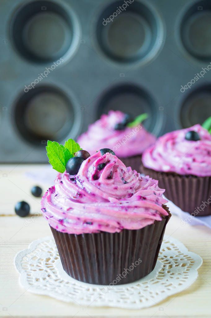 Muffin with curd cream and black currant on wooden background
