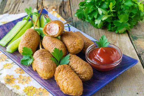 Corn dogs fried in cornmeal batter served on a ceramic plate. Wo