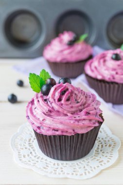 Ahşap arka plan üzerinde lor krema ve siyah frenk üzümü ile Muffin