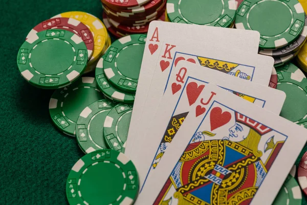 Casino chips and ace, king queen jack of spades on green table