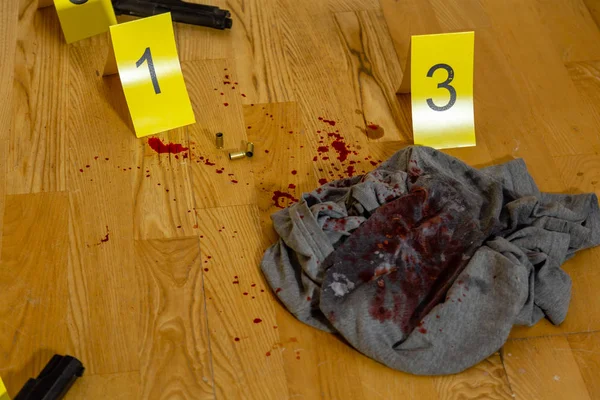 弾丸のケーシング 血まみれの服と銃犯罪現場でマーカーの横にあります — ストック写真