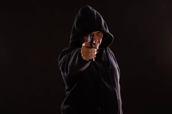 Homem com capuz preto aponta pistola — Fotografia de Stock