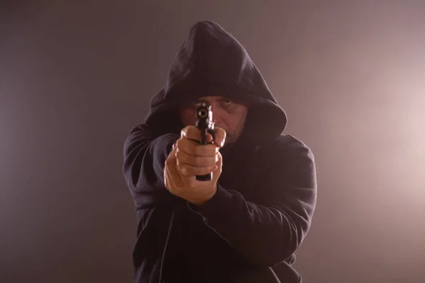 Homem com capuz preto aponta pistola — Fotografia de Stock