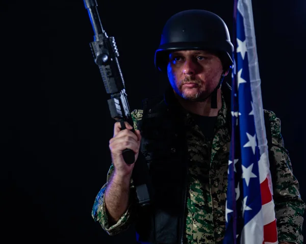 Soldado segurando rifle de assalto e bandeira dos EUA — Fotografia de Stock