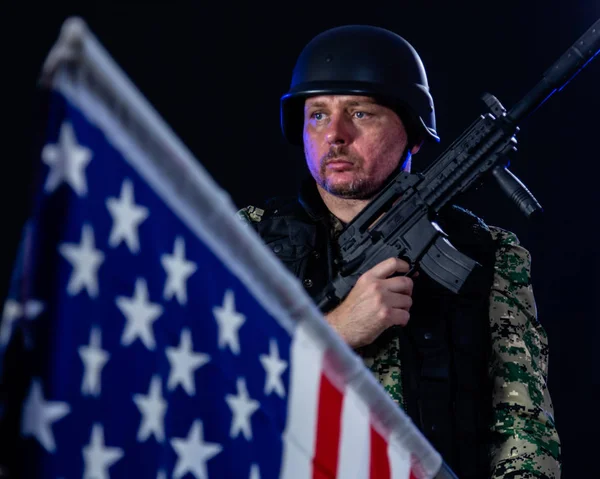 Soldado segurando rifle de assalto e bandeira dos EUA — Fotografia de Stock