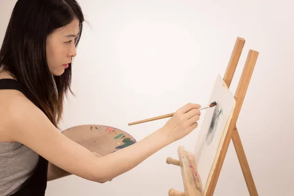 Artista asiático-americano pintando sobre un caballete — Foto de Stock