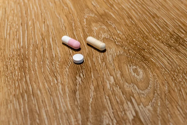 Капсулы и таблетки на столе — стоковое фото