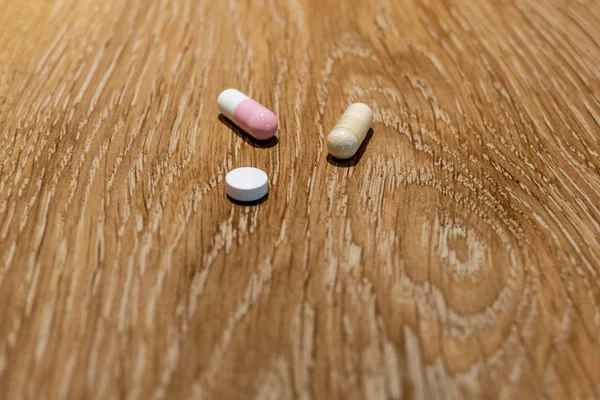 Капсулы и таблетки на столе — стоковое фото