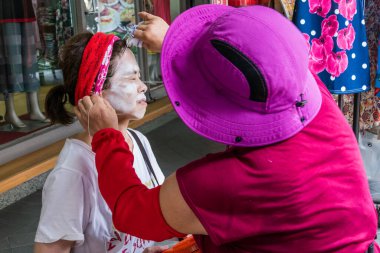 YENİ TAIPEI CITY, TAIWAN - 23 HAZİRAN: Tanımlanamayan kadın kaldırımdaki bir güzellik uzmanı tarafından geleneksel bir ip yüzü yaptırıyor.