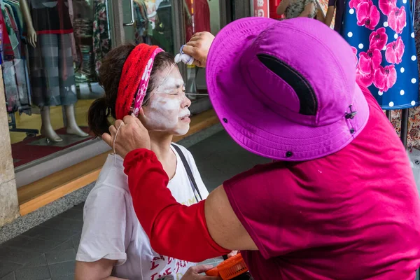 YENİ TAIPEI CITY, TAIWAN - 23 HAZİRAN: Tanımlanamayan kadın kaldırımdaki bir güzellik uzmanı tarafından geleneksel bir ip yüzü yaptırıyor.