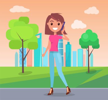 Hoş, genç, şık bir kız telefonla konuşuyor, yeşil yaz parkında yürüyor, şehir manzarası arka planında.