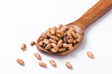 Beyaz arka plan üzerinde tahta kaşık çiğ barbunya yığını