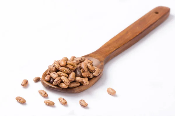 Beyaz arka plan üzerinde tahta kaşık çiğ barbunya yığını