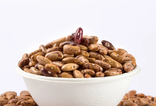 Beyaz arka planda beyaz kase çiğ barbunya yığını