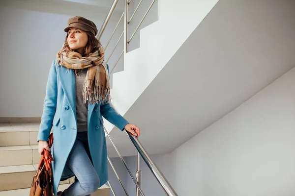 Paltolu iş kadını alışveriş merkezinde merdivenlerden iniyor. Alışveriş. Moda