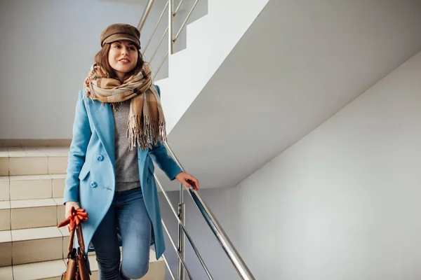 Paltolu iş kadını alışveriş merkezinde merdivenlerden iniyor. Alışveriş. Moda