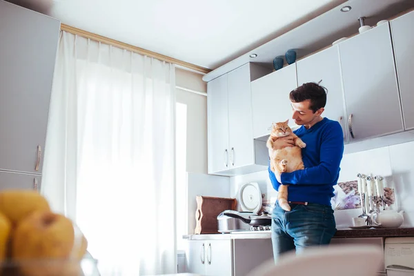 Mutfakta kedi tutan yakışıklı genç adamın portresi.