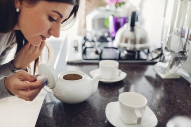 Kadın masadaki seramik fincana çay dolduruyor.