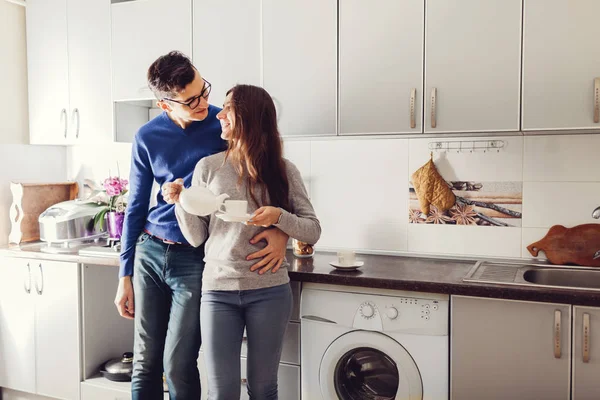 Joven linda pareja abrazo y beber té en la cocina — Foto de Stock