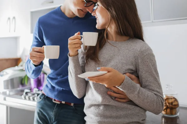 young cute couple hugging and drinking tea in the kitchen