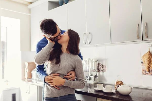 Young couple in the kitchen hugging and kissing — Stock Photo, Image