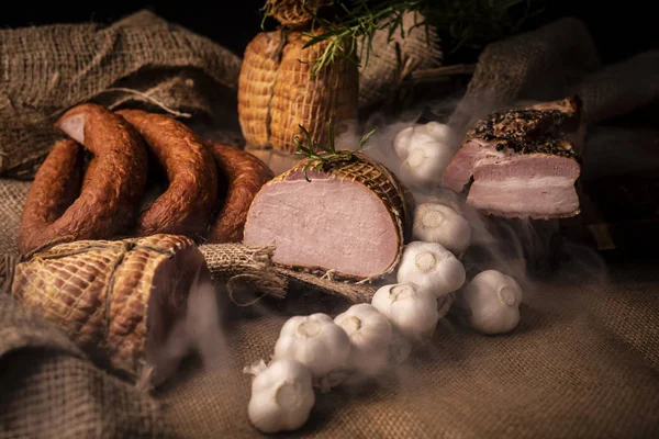 Gerookte varkensvlees ham, spek en worst. Een zelfgemaakte samenstelling van koude vleeswaren. — Stockfoto