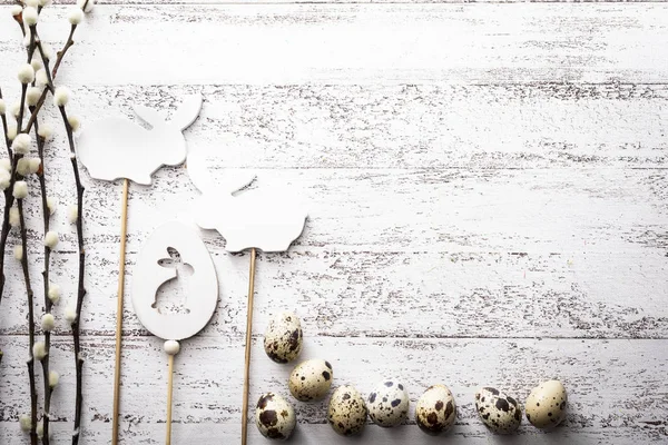 Easter holiday with quail eggs, willow branches and easter bunny on a wooden background — Stock Photo, Image