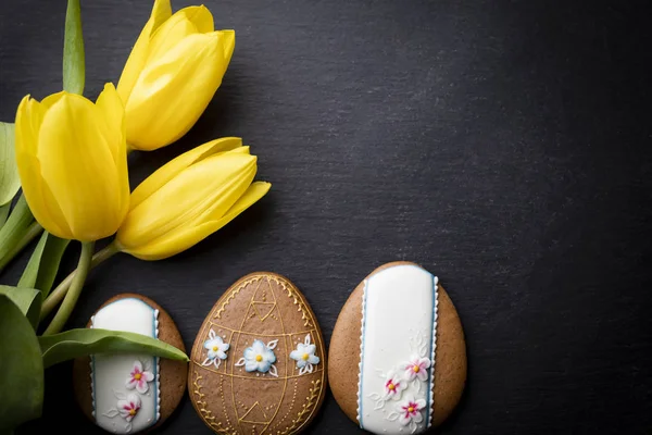 Easter background. Cookies and flowers on a black background. — Stock Photo, Image