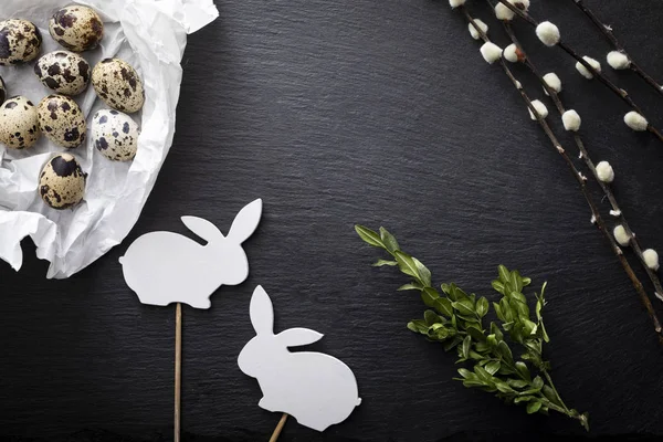 Easter background.  Natural quail eggs, willow branches and easter bunny on a dark background — Stock Photo, Image