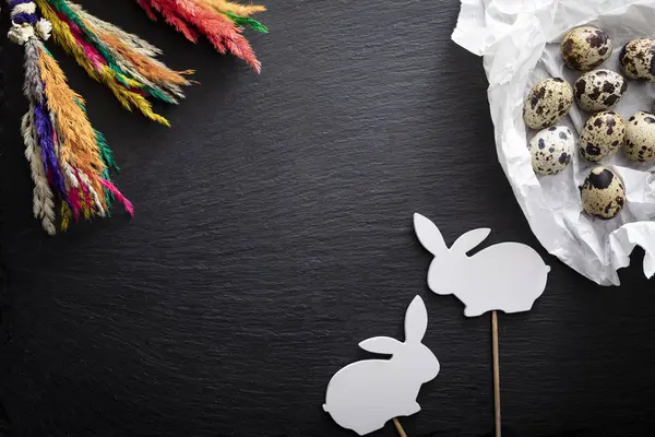 Natural quail eggs, willow branches and easter bunny on a dark background — Stock Photo, Image