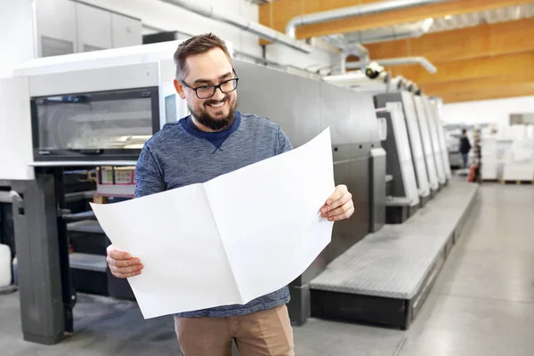 Una tipografia. L'uomo soddisfatto sta guardando la stampa . — Foto Stock