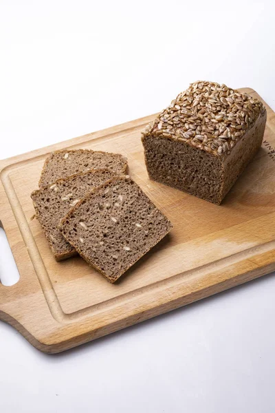 Pane con chicchi. Pane di segale tradizionale su tavola di legno su fondo bianco . — Foto Stock