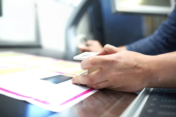 The printer at the stage watches the print quality through a magnifying glass.